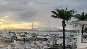 A marina with multiple boats docked, a palm tree, and a mountainous backdrop during sunset. - Beautiful 2bd 2 ba villa w/lush yard, gated community 15 min from Manuel Antonio (Quepos)