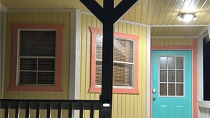 Ein Haus mit gelber Fassade, einer türkisblauen Tür und einem schwarzen Geländer.
