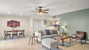 A modern living room with a dining area, a ceiling fan, and a kitchen in the background. - Biltmore Condo w/ Heated Pool! (Phoenix)