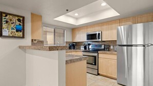 A modern kitchen with a central island, stainless steel appliances, and wooden cabinets. - Biltmore Condo w/ Heated Pool! (Phoenix)