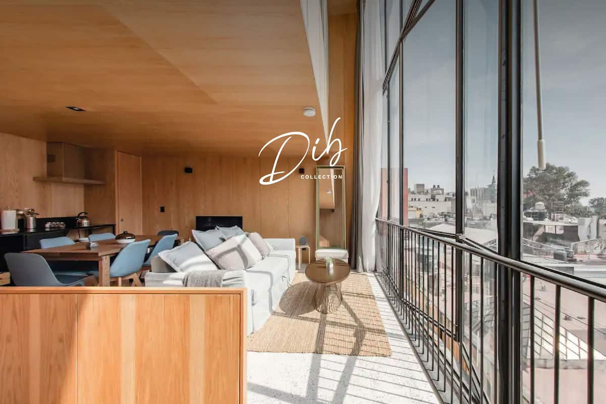 Un interior moderno con comedor, sofá y un amplio ventanal con vistas a la ciudad.