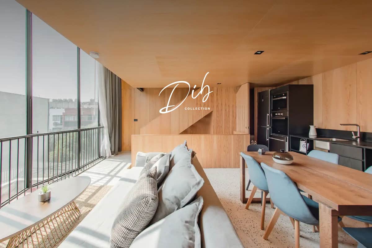 Un apartamento moderno con balcón, sofá, comedor y cocina.