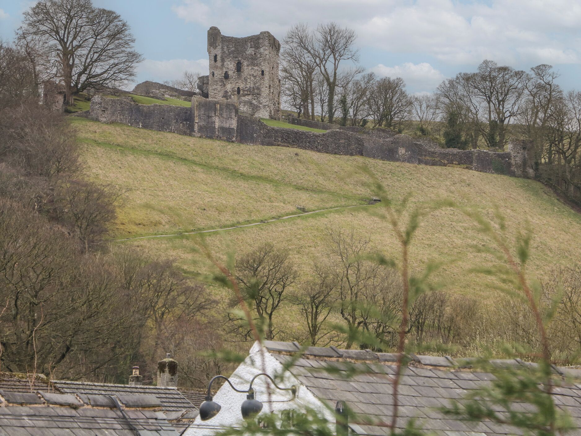 A historic stone castle on a hill with a pathway leading up to it.