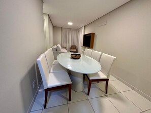 Un comedor con una mesa redonda, sillas blancas acolchadas y un cuenco sobre la mesa.
