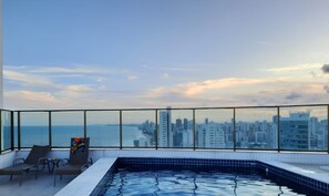 A rooftop pool with a cityscape view, lounge chairs, and a tiled floor. - HY Parque Atlântico (Recife)