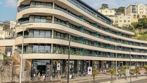 A modern multi-story building with curved balconies and large windows.