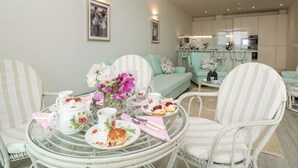A dining area with a round glass table, striped chairs, and a floral centerpiece.