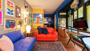 Ein lebhaftes Wohnzimmer mit einem roten Sofa, einem blauen Sitzsofa und einem gemusterten Teppich.