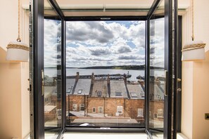 A view from a room with a large window overlooking a body of water and a distant island.
