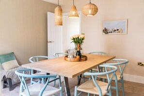 A dining area with a wooden table, light blue chairs, and wicker pendant lights.