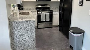 A kitchen with white cabinets, a black microwave, a stainless steel stove, and a black refrigerator. - Modern Universal Orlando (Orlando)