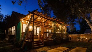 Une cabane en bois avec une véranda, une planche de surf et des guirlandes lumineuses.