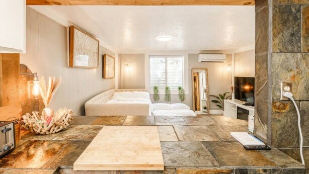 A room with a bed, a TV, and a stone wall.