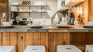 A kitchen with wooden cabinets, a countertop with dishes and glasses, and a stove.