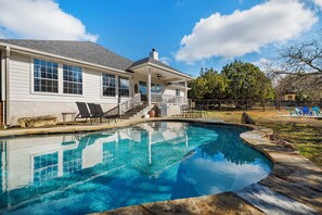 Une maison avec une piscine, une véranda et un escalier menant à l’entrée.