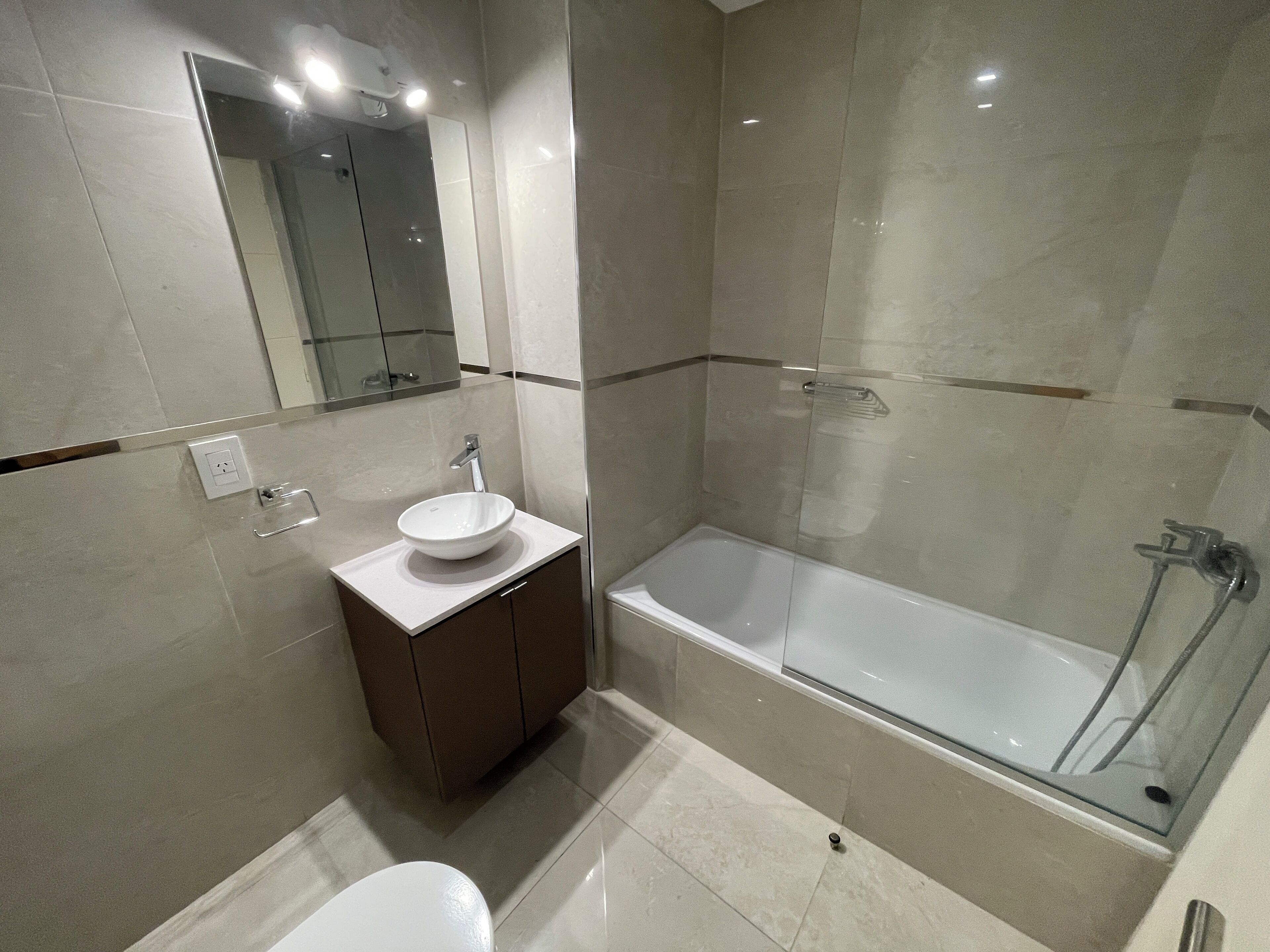 A modern bathroom with a sink, mirror, and bathtub.