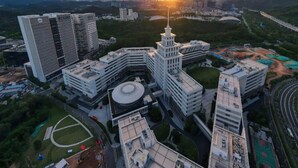 A high-rise building complex with multiple structures, including a central tower and surrounding buildings, surrounded by greenery and a road network. - Lavande Hotel Shenzhen University city Metro Station (Shenzhen)
