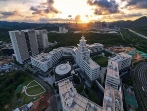 A high-rise building complex with multiple structures, including a central tower and surrounding buildings, surrounded by greenery and a road network. - Lavande Hotel Shenzhen University city Metro Station (Shenzhen)