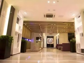 A modern hotel lobby with a reception desk, seating areas, and a large wall clock. - Lavande Hotel Shenzhen University city Metro Station (Shenzhen)