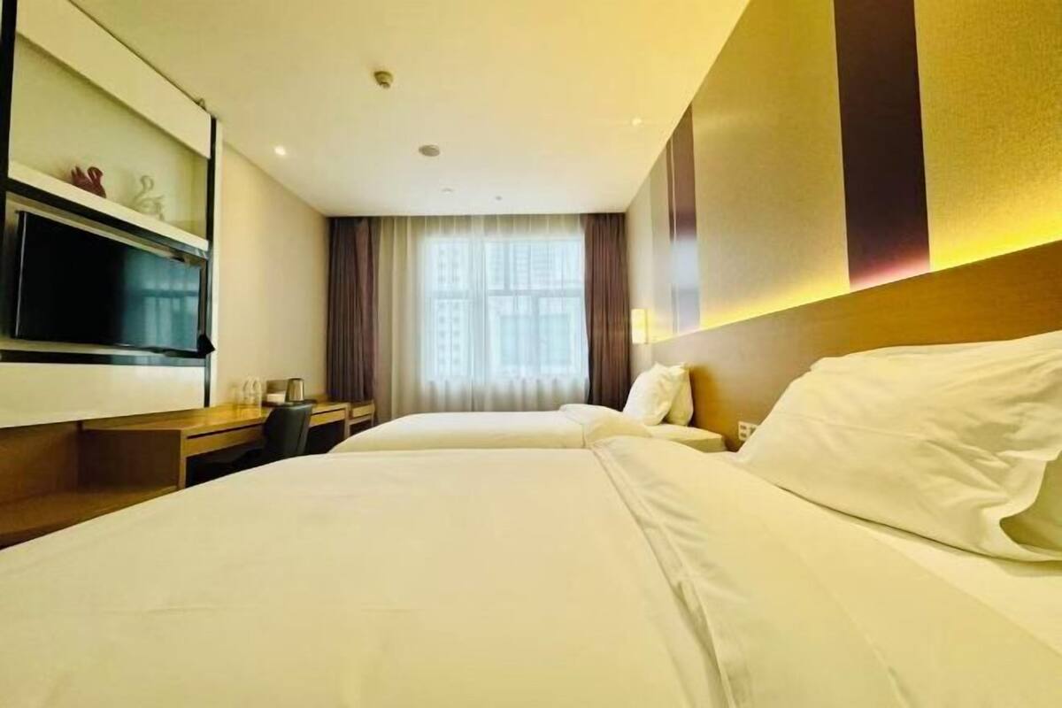 A hotel room with a bed, a desk, a TV, and a window with curtains.