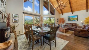 A spacious living area with a dining table set for four, surrounded by leather sofas and a fireplace. - Best Mountain Views in Estes! Large Family Home (Estes Park)