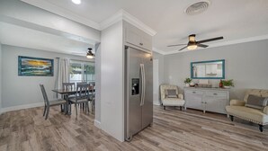 A modern kitchen with a stainless steel refrigerator, wooden flooring, and a dining area with a table and chairs. - Endless Summer Escape Near SK (Sarasota)
