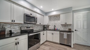 A modern kitchen with white cabinets, stainless steel appliances, and a tiled backsplash. - Endless Summer Escape Near SK (Sarasota)