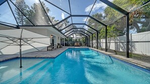 A swimming pool with a covered area, surrounded by a fence and trees. - Endless Summer Escape Near SK (Sarasota)
