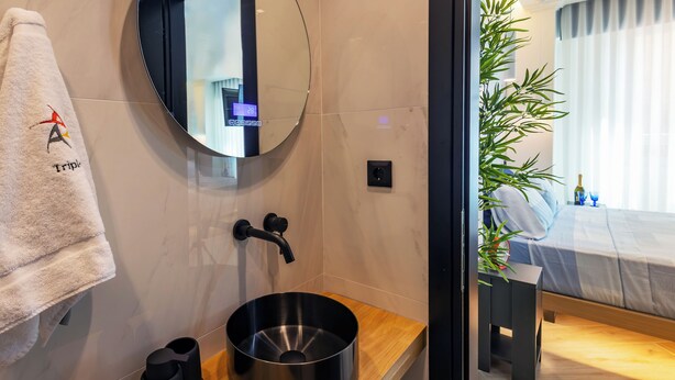 A modern bathroom with a round mirror, a black sink, and a towel rack.