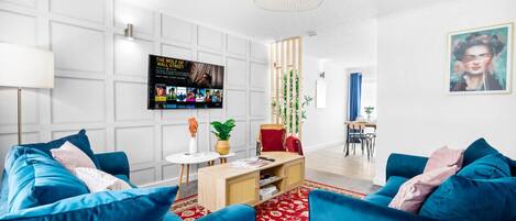 Una sala de estar moderna con un sofá azul, una mesa de centro de madera y una alfombra roja estampada.