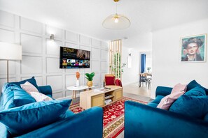 A modern living room with a blue sofa set, a wooden coffee table, and a red patterned rug. - Stylish 3 Bedroom House - Parking - Garden (Birmingham)