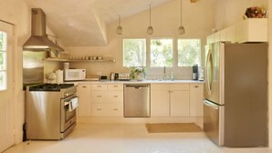 Una cocina moderna con electrodomésticos de acero inoxidable, armarios de madera e iluminación colgante.