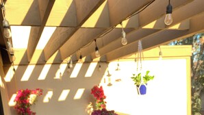 A patio with a round table and chairs, potted plants, and hanging light bulbs. - COZY UCSD/La Jolla Condo 2bd, 10-15 min from just about anywhere in the city (San Diego)