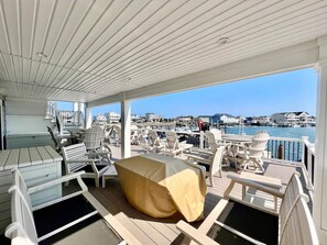 Une terrasse extérieure couverte, aménagée avec des sièges et offrant une vue sur le port de plaisance.