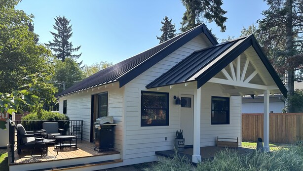 Une petite maison de plain-pied dotée d’un patio couvert, d’un barbecue et d’une terrasse en bois.
