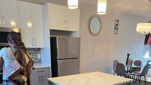 Una cocina moderna con armarios blancos, una isla de mármol y taburetes de bar.