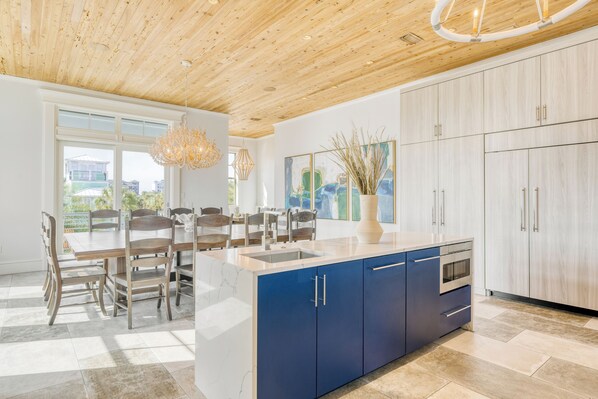 Una cocina moderna con techo de madera, armarios azules y una isla grande.