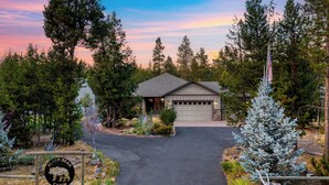 Une cabane avec un garage, entourée d’arbres, et une pancarte indiquant qu’il s’agit de la « Cabane de l’Ours Noir ».