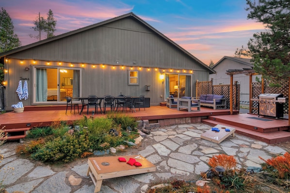 A covered patio with outdoor furniture, a wooden deck, and a small game table.