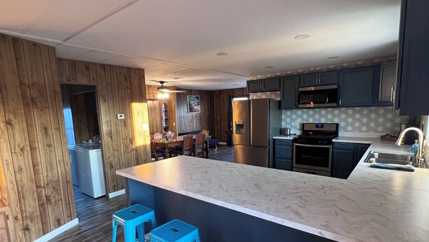 A modern kitchen with a central island, bar stools, wooden flooring, and built-in appliances. - Beach and Launch Access (Mohave Valley)