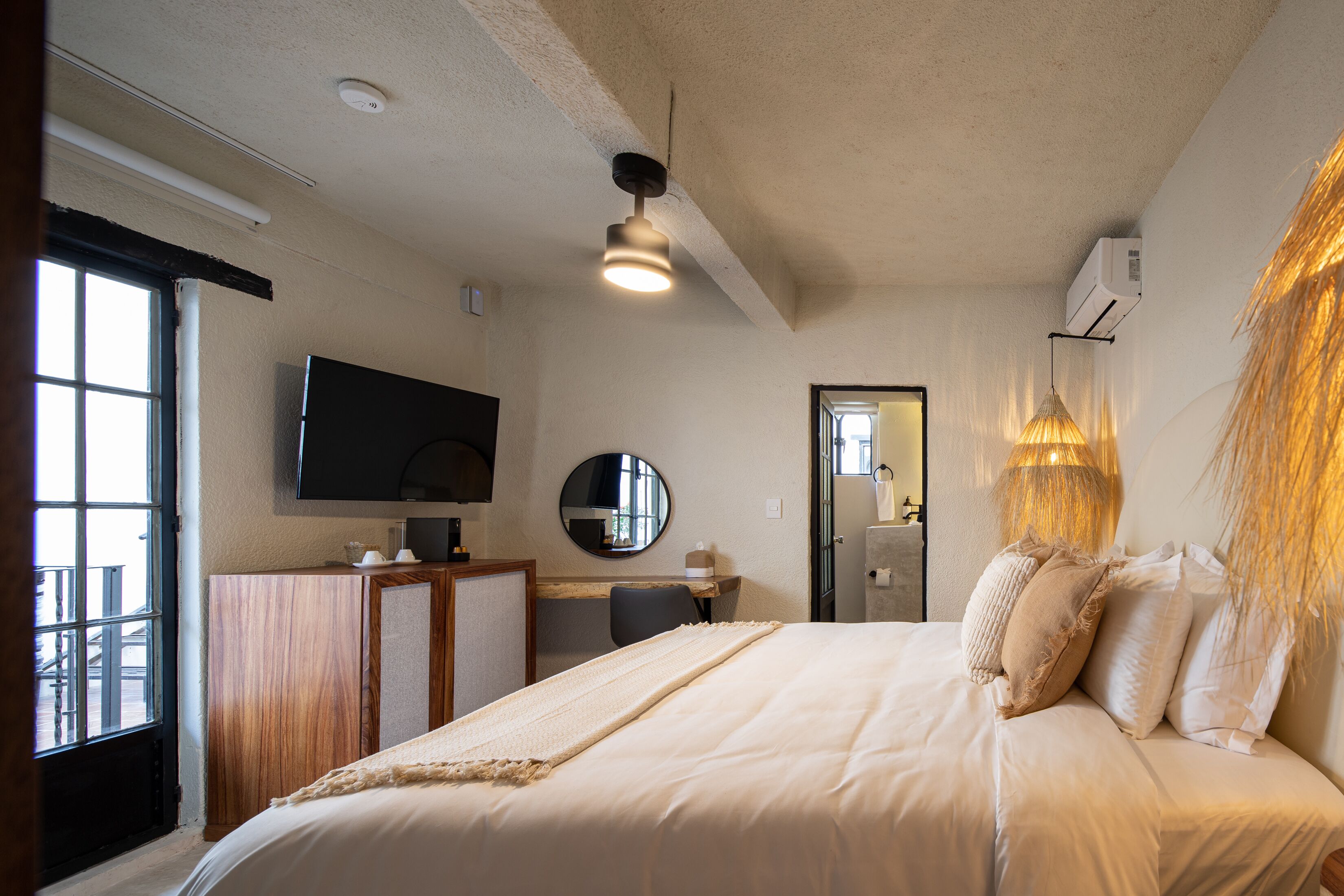 A hotel room with a bed, a desk, a chair, a television, and a window.