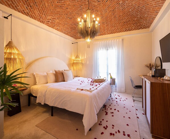 A spacious bedroom with a large bed, a chandelier, and a brick ceiling. - HOLT Hotel del Pueblito (San Miguel de Allende)
