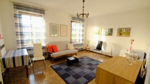 En stue med sofa, stole, et sofabord, et spisebord og en lysekrone.