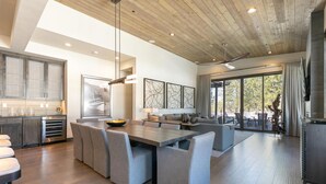 Una cucina moderna con isola centrale, sedute rivestite in grigio e un ampio tavolo da pranzo.
