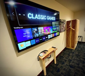 A flat-screen TV mounted on a wall displaying a streaming service interface with various content options. - Bear Mountain -Suite 8 (Grants Pass)