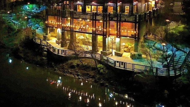 Un edificio de varios pisos con un balcón y un muelle que se extiende sobre el agua.
