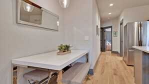 Une cuisine moderne avec un plan de travail blanc, des appareils en acier inoxydable et un banc sous le plan de travail.
