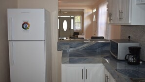 Eine Küche mit einem weißen Kühlschrank, einer Mikrowelle und einer Kaffeemaschine auf der Arbeitsplatte.