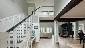 A spacious interior with a staircase, a living area with a fireplace, and a kitchen in the background. - Secluded Cove and Dock at Tim's Ford (Winchester)