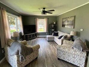 Relax in this stylish living room with a large flat-screen TV, two sofas, and a ceiling fan.